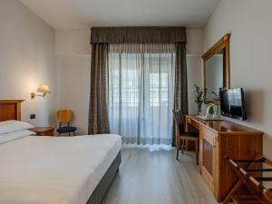 a hotel room with a bed and a desk and a television at Hotel Diplomatic in Rome