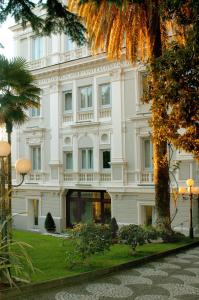un grande edificio bianco con un albero di fronte di Hotel Flora a Frascati