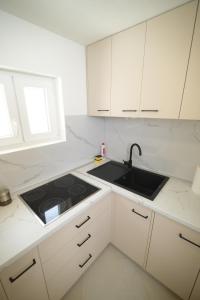 a white kitchen with a sink and a stove at Planinski vuk chalet in Žabljak +18 photos