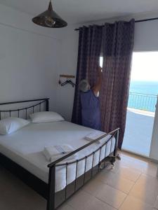 a woman looking out of a bedroom window at the ocean at Valentina Rooms in Qeparo