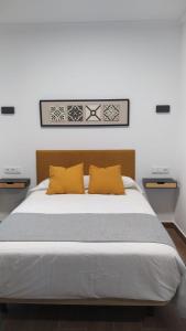 a bedroom with a large bed with yellow pillows at Hostal Andalucía in Chipiona