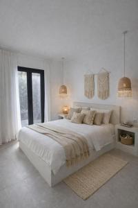 a white bedroom with a large bed and two lamps at Atlantis Four in Éxo Goniá