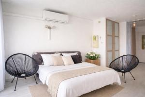 a bedroom with a large bed and two chairs at centre port le cocon 4 couchages in Cap d'Agde