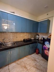 a kitchen with blue cabinets and a sink at AM Living in Ghaziabad