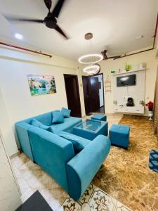a living room with a blue couch and a tv at AM Living in Ghaziabad