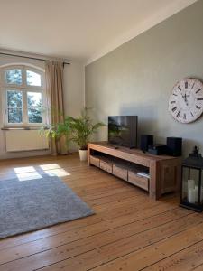 a living room with a television and a clock on the wall at Ferienwohnung ehemalige Revierförsterei "uns Lütt" in Kuhstorf