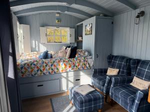 a bedroom with a bed and two chairs at Bluebell Shepherd's Hut in Llanfair