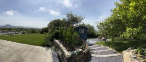 a garden with a stone wall and a blue house at Bluebell Shepherd's Hut in Llanfair