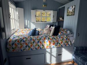 a bedroom with a bed with a colorful quilt at Bluebell Shepherd's Hut in Llanfair