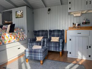 a bedroom with two blue chairs and a bed at Bluebell Shepherd's Hut in Llanfair +19 photos