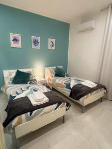 two twin beds in a room with blue walls at Nicola's Apartments in Santa Maria La Carità