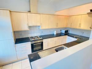 a kitchen with white cabinets and black counter tops at Catherines House Kings Cross Area in London