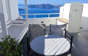 a table and chair on a balcony with a view of the ocean at Yposkafo Suites - Villa - Santorini in Fira