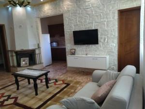 a living room with a couch and a stone wall at The Garden Guest House in Divjakë