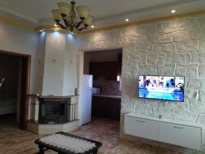 a living room with a tv on a stone wall at The Garden Guest House in Divjakë +55 photos
