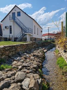 a house and a stone wall next to a river at MANSARD - Bozsok in Bozsok