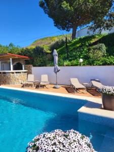 a swimming pool with chairs and an umbrella and flowers at B&B la Madrugada in Cómpeta +54 photos
