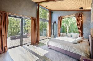 a bedroom with a large bed and large windows at Ramiau - su gamta in Kareivonys