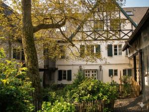 a white house with a tree in front of it at Rhein River Guesthouse - direkt am Rhein in Leverkusen +41 photos