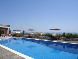 a swimming pool with umbrellas on top of a building at Abelonas Village in Megalochori