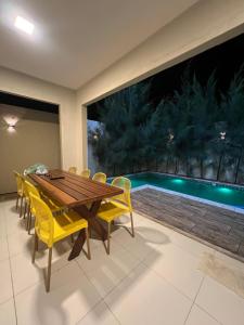 a dining room with a wooden table and yellow chairs at Casa Temporada Trairi in Trairi
