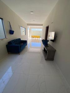 a living room with a blue couch and a flat screen tv at Casa Temporada Trairi in Trairi