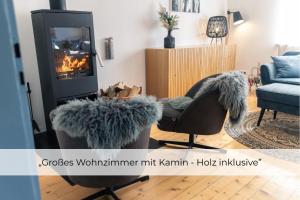 a living room with a chair and a fireplace at Landhaus Paco Ferienhaus für 12 Personen mit Alpakas, Sauna & Kamin in Blaufelden
