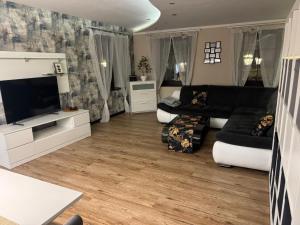 a living room with a black couch and a tv at Apartament Alan in Kłodzko
