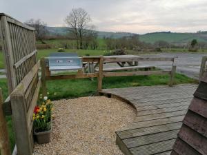 a wooden bench sitting on a wooden walkway next to a river at Castle View Glamping - 2 Cefn in Llandrindod Wells