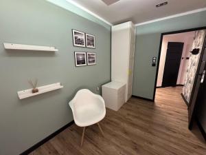 a room with a white chair and a hallway at Apartament Alan in Kłodzko