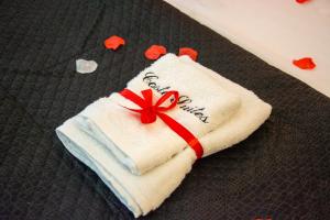 a white towel with a red bow on a bed at Hesperia Suite - Jacuzzi & Garden in Corigliano dʼOtranto