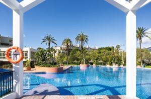 a swimming pool at a resort with palm trees at EL ESTUDIO DE LA PLAYA Sunny Holidays Benalbeach in Benalmádena