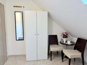a white cabinet with two chairs and a table at Ubytovna u Maiky in Libochovice