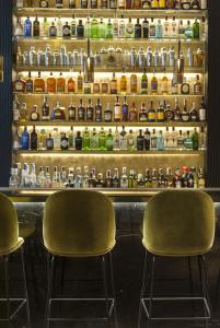 two chairs sitting in front of a bar with bottles at Hotel Mercer Sevilla 5 GL in Seville +39 photos