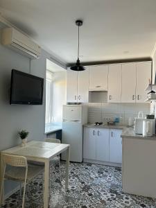 a kitchen with white cabinets and a table and a tv at Sisters apartment Val in Chernihiv