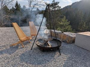 a fire pit with two chairs and a grill at Pine Hill RUBY with free jacuzzi in Rakitna