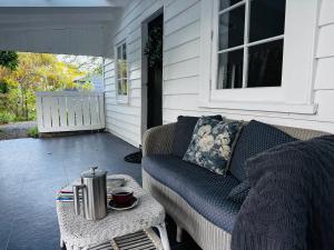a porch with a couch and a coffee table at Pinegrove Cottage - Greytown Getaway in Woodside