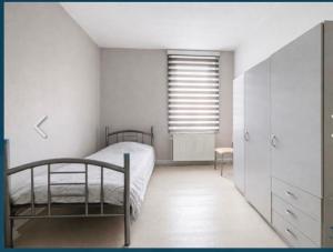 a white bedroom with a bed and a window at Zenitude in Jumet