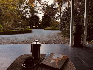 a table with a book and a candle on a porch at Pinegrove Cottage - Greytown Getaway in Woodside