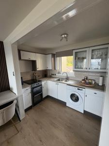 a kitchen with white cabinets and a sink and a dishwasher at View of the Isles 2 in Largs