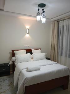 a bedroom with a large bed with white pillows at Résidence ABOMO'S in Kribi