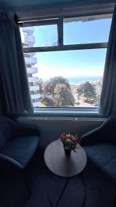a living room with a table and two chairs and a window at Russel Court Hotel Bournemouth Central in Bournemouth