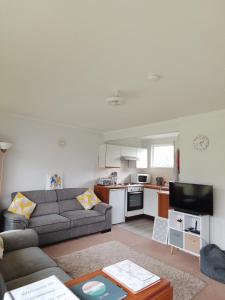 a living room with a couch and a kitchen at The Warren Chalet in Cromer