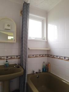 a bathroom with a green tub and a sink at The Warren Chalet in Cromer