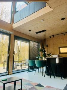 a dining room with a table and chairs and windows at Chill ChaTka Osowiec Las&SPA pod Warszawą in Osowiec