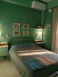 a bedroom with green walls and a bed with a blanket at iliolithos rooms in Kardamyli