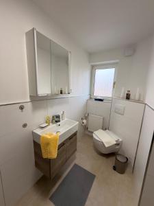 a white bathroom with a sink and a toilet at Miras Guesthouse Ferienwohnung in Lengerich +19 photos
