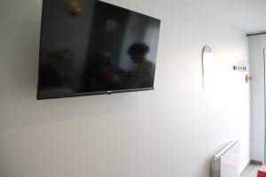 a flat screen tv hanging on a white wall at chez laetitia proche du puy in La Flocellière