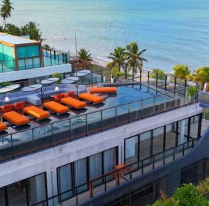 an apartment building with orange lounge chairs and the beach at Cabo Branco Flat Amsterdam in João Pessoa