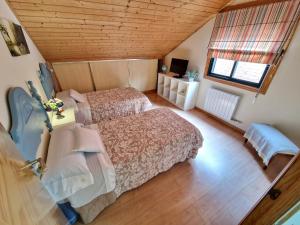 an attic bedroom with two beds and a window at Adro Redondela in Redondela